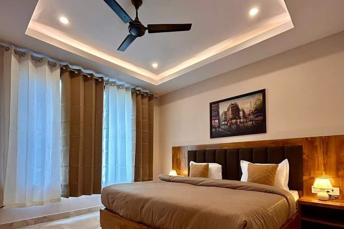 Un dormitorio moderno con una cama grande, un ventilador de techo y una mesita de noche con lámpara.