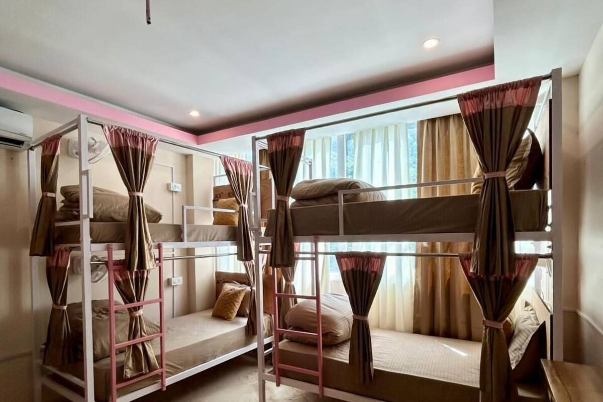 Una habitación con literas, suelo de mármol y una ventana con cortinas.