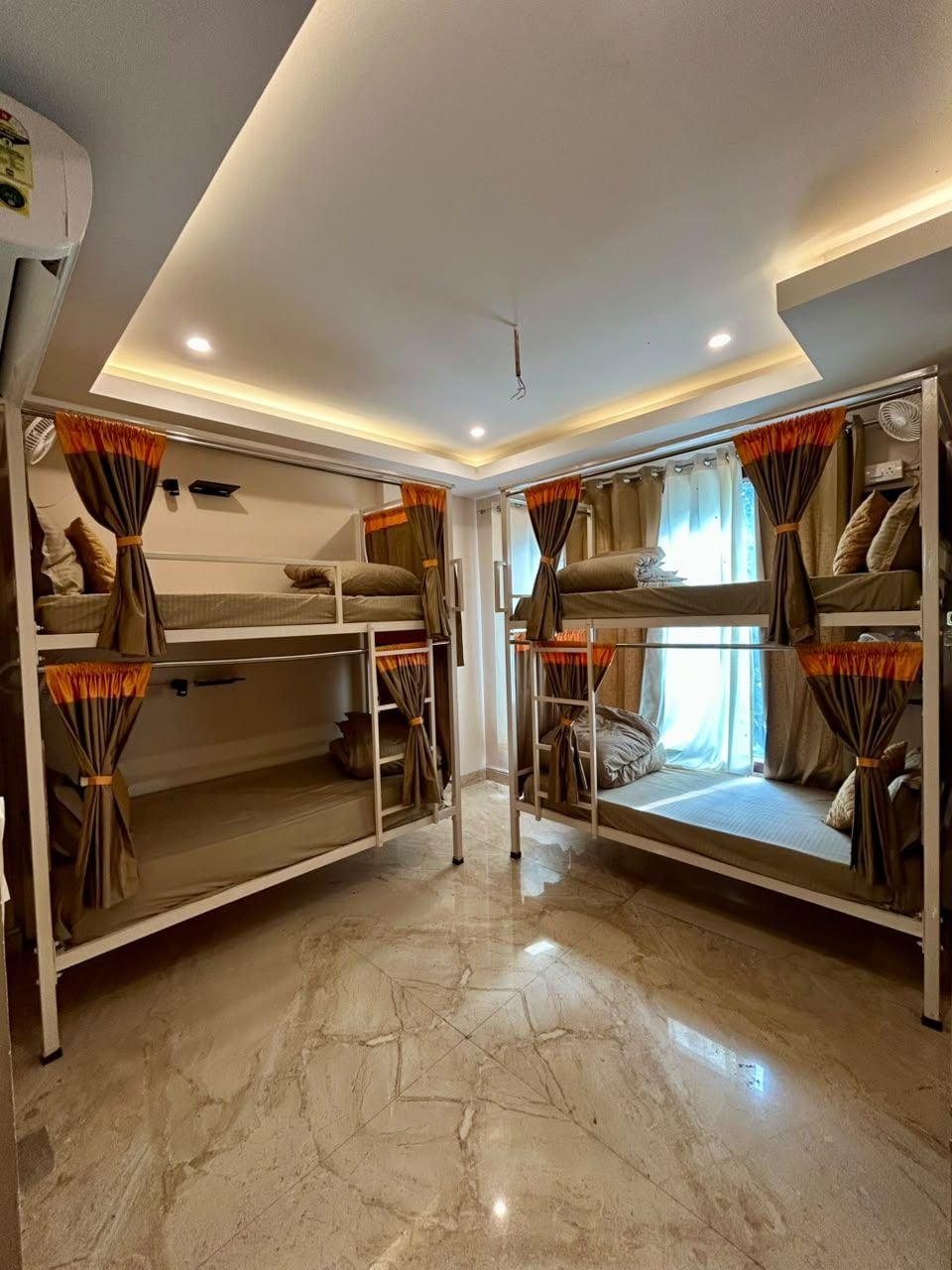 A room with bunk beds, a ceiling fan, and a window with curtains.