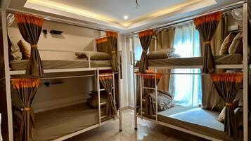 A room with bunk beds, a ceiling fan, and a window with curtains.