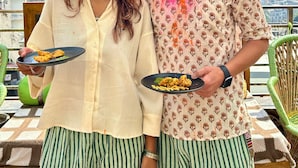 Two people holding plates of food on a terrace with a mountainous backdrop. - Namaste Hostel Rishikesh (Rishikesh)