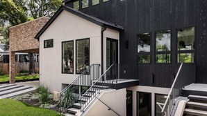 A modern two-story house with a black exterior, white walls, and large windows. - Furnished Modern Luxury Retreat (Austin)