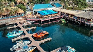 A marina with boats docked, a building with a blue roof, and a dock with a thatched roof. - Furnished Modern Luxury Retreat (Austin)