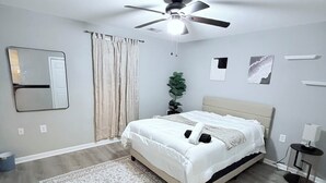 A bedroom with a bed, a ceiling fan, a mirror, a plant, and a rug. - Large 5BR Home Sleeps 12 Fireplace  ADA-Friendly Access (Halethorpe)