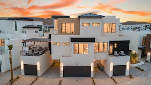 A modern multi-story residential building with a garage, outdoor seating area, and a well-lit entrance. - Pearl Beach B: Lagoon Front + Beach Access (St. George)