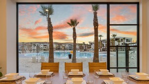 Tavola da pranzo imbandita per sei con vista sulla spiaggia e sulla piscina al tramonto.