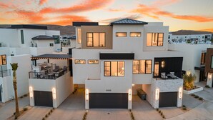 Un moderno edificio residenziale a più piani con garage, area salotto esterna e ingresso ben illuminato.