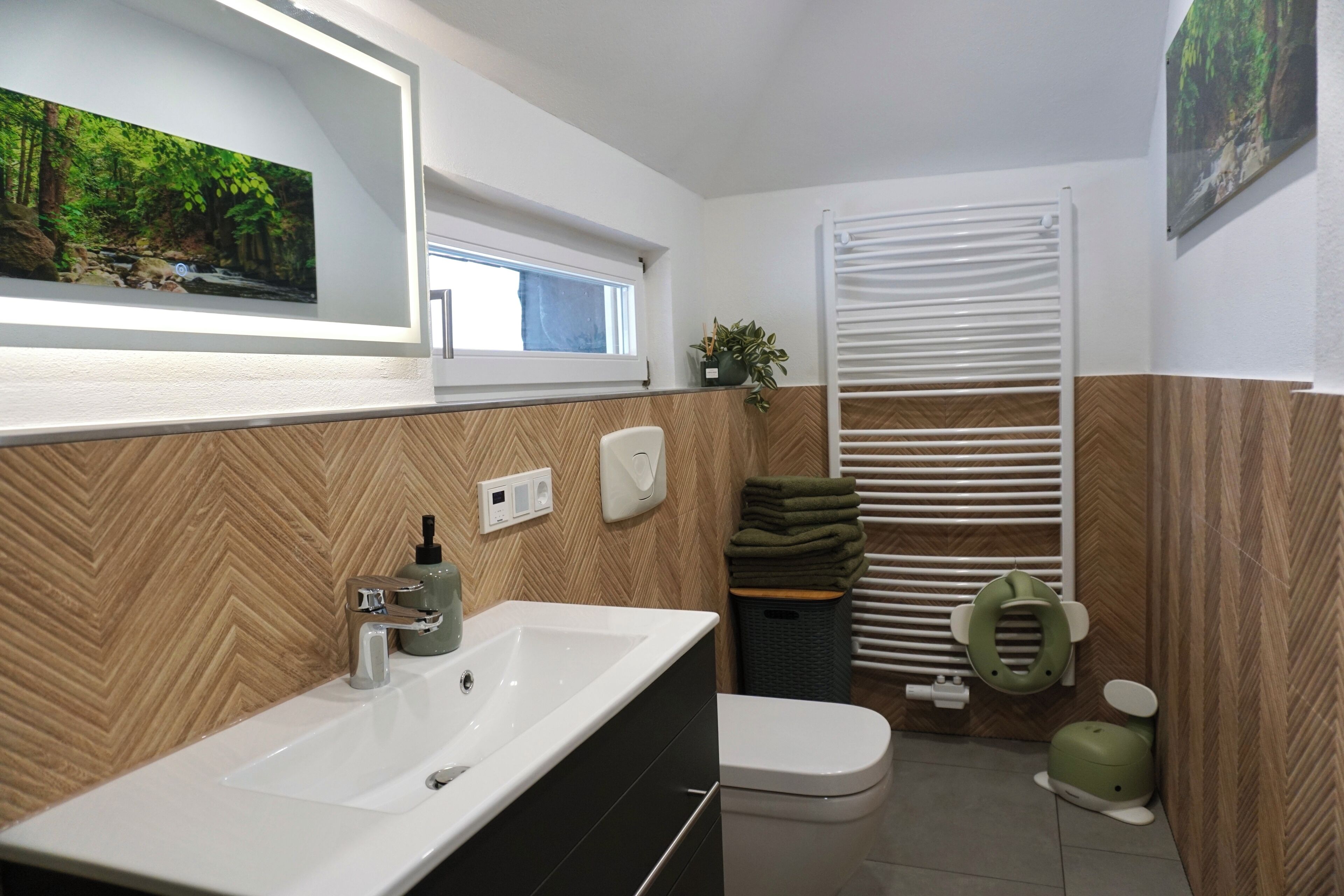 Un baño moderno con un espejo grande, un lavabo, un inodoro y una zona de ducha.
