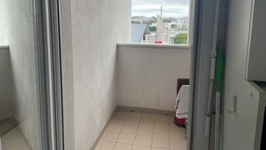 Ein kleiner Balkon mit Blick auf eine Stadtansicht, ein Fliesenboden und eine Tür, an der ein Handtuch hängt.