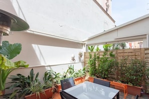 A patio with a table and chairs, surrounded by potted plants and a wooden fence. - Vatican Vittoria Suites (Rome)