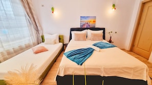A hotel room with two beds, a painting on the wall, and a window with curtains.