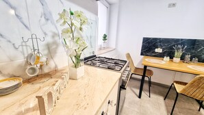 A modern kitchen with a gas stove, marble countertops, and a dining area with a table and chairs.