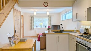 Una cocina moderna con una mesa de comedor de madera, horno empotrado y una ventana con cortinas.
