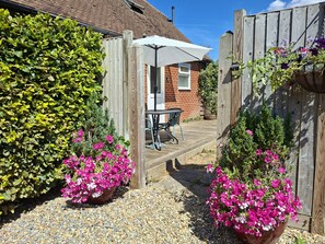 A garden with a wooden fence, a patio table, and chairs. - Dandydills -  an annexe that sleeps 2 guests  in 1 bedroom (Colworth)