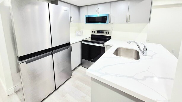 A modern kitchen with stainless steel appliances, a microwave, and a sink. - Niagara Cozy Suite - Modern 2bed 15 min to Falls (Thorold)