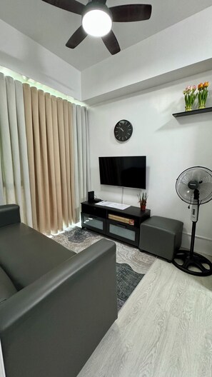 Een moderne woonkamer met een flatscreen televisie, een plafondventilator en een bank.