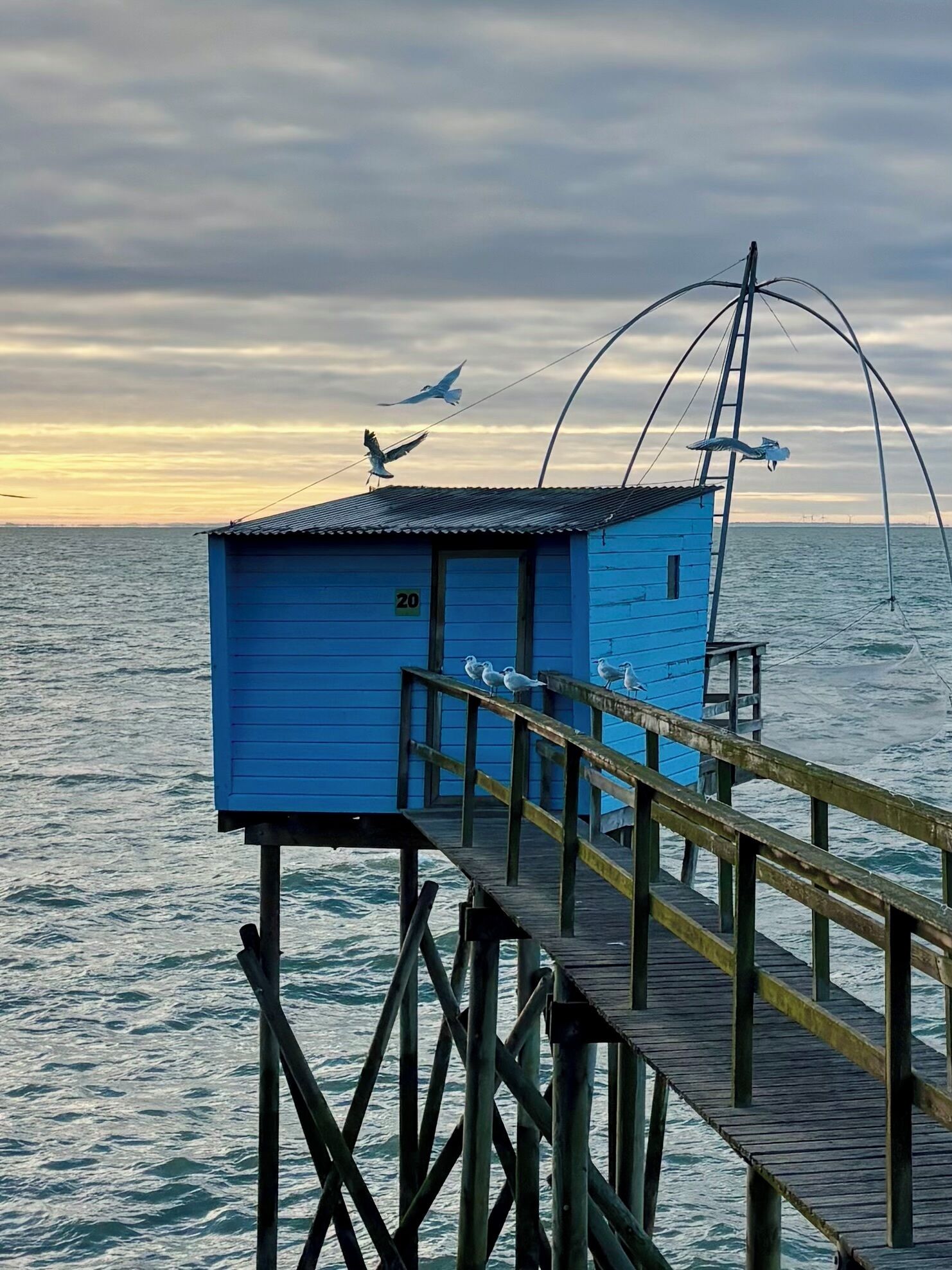 A blue wooden structure with a number '20' on it, connected to a pier extending over the water.