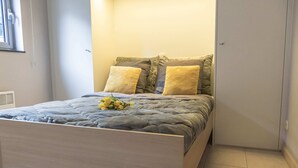 A bedroom with a bed, pillows, and a bouquet of flowers.