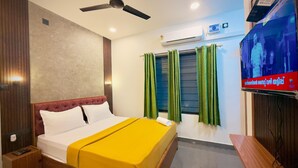 A hotel room with a bed, a ceiling fan, an air conditioning unit, and a television on the wall. - NAKSHATRA (Neyyattinkara)