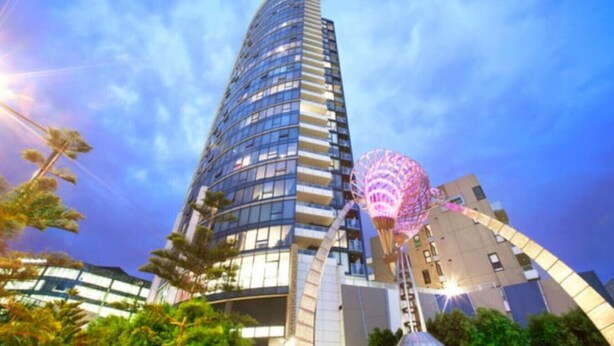Un immeuble moderne de grande hauteur, doté d’une façade incurvée et de nombreux balcons.