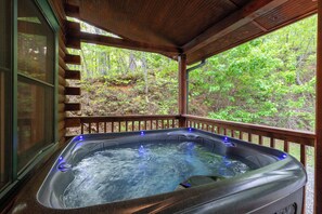 Un jacuzzi con terraza de madera y vista al bosque.