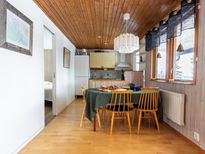 Un comedor con una mesa de madera, sillas, un mapa en la pared y una cocina al fondo.