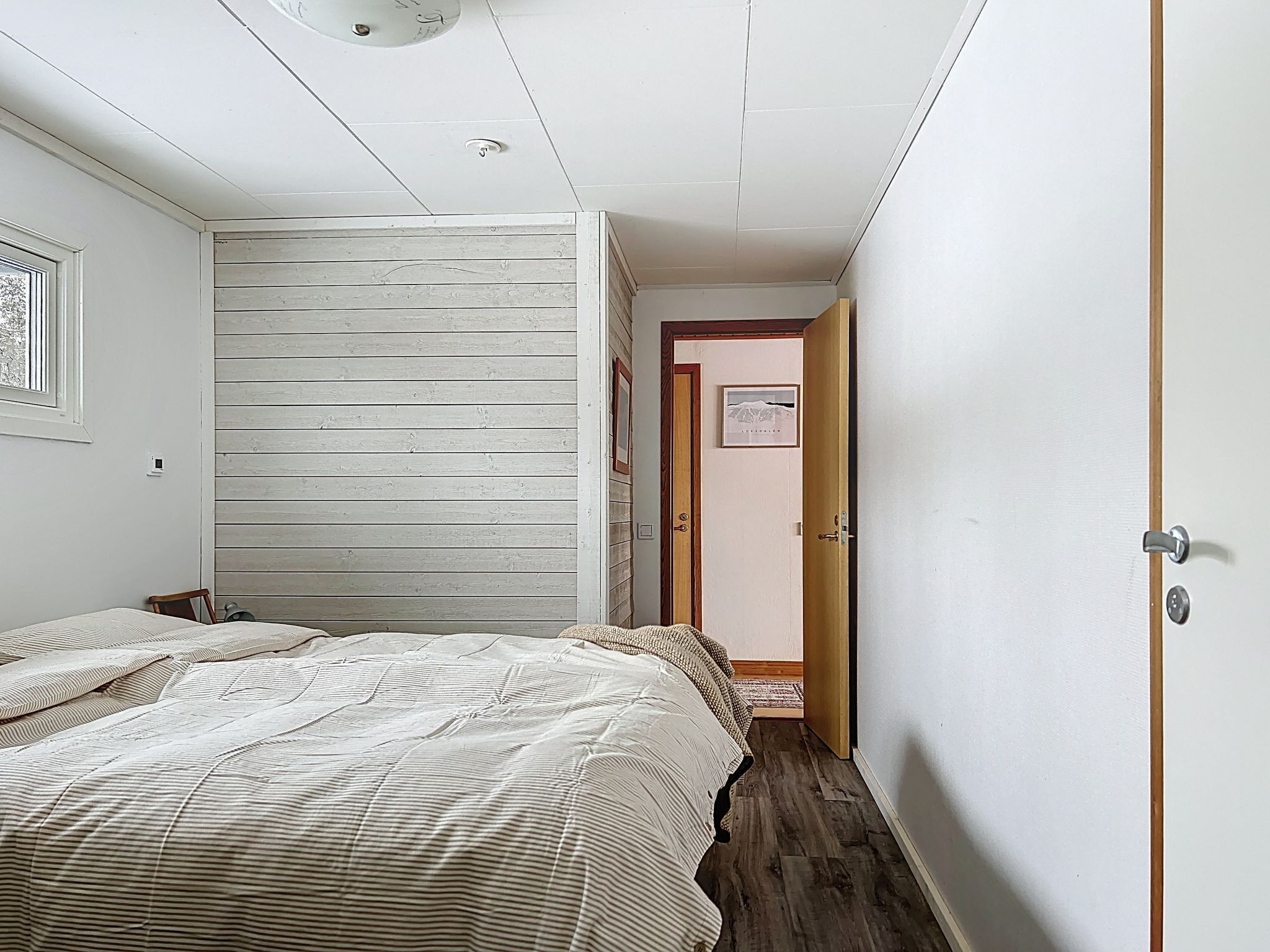 Une chambre à coucher avec un lit, un mur en bois, une porte et un petit tapis.