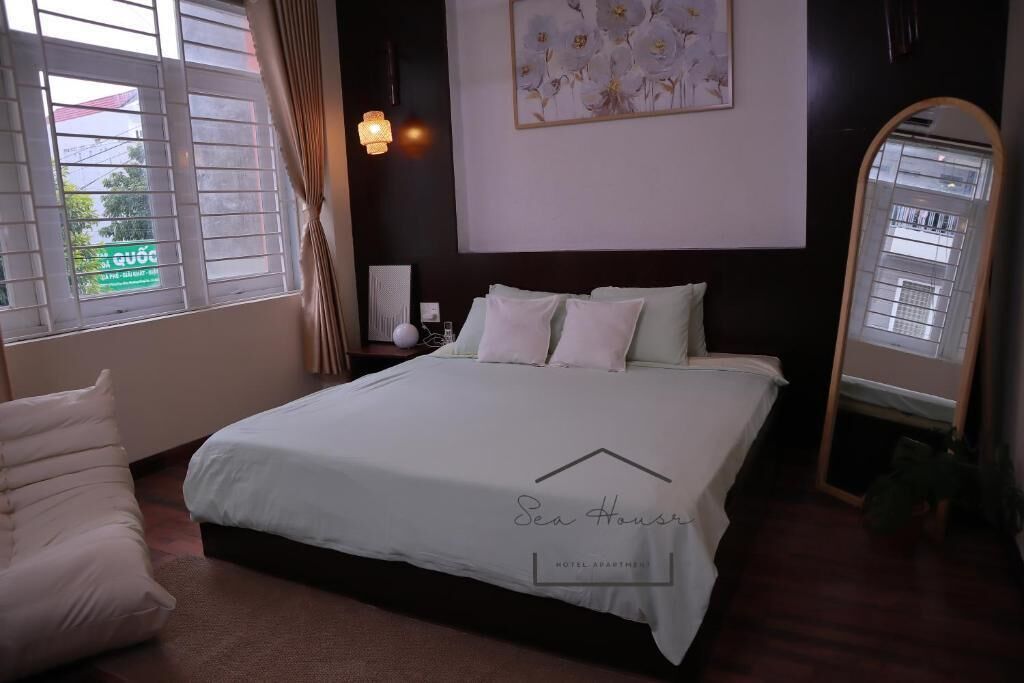 Un dormitorio de hotel con una cama, una mesita de noche, un espejo y una ventana con cortinas.