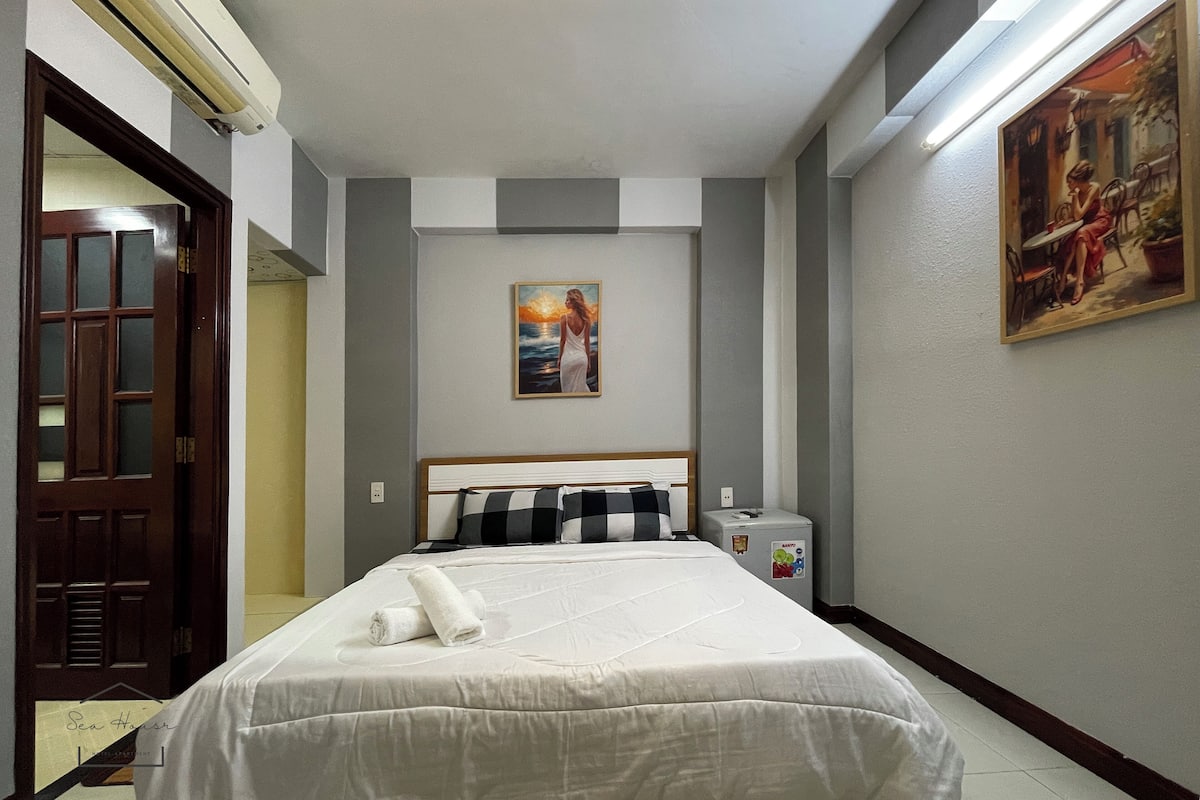Una habitación de hotel con una cama, un cuadro en la pared y una puerta.