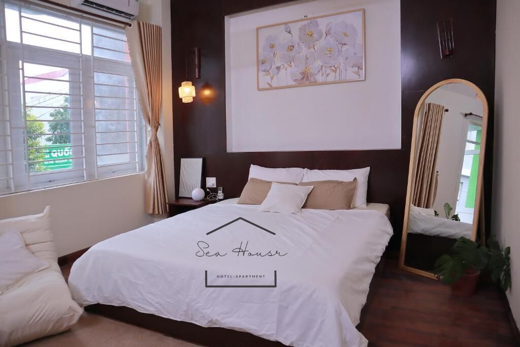 Une chambre d’hôtel avec un grand lit, une table de chevet, un miroir et une fenêtre avec des rideaux.