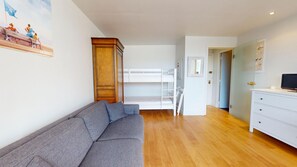 A room with a grey sofa, a wooden wardrobe, a white dresser, and a bunk bed. - Le Studio Baulois Comfort and proximity to the beach in La Baule (La Baule-Escoublac)