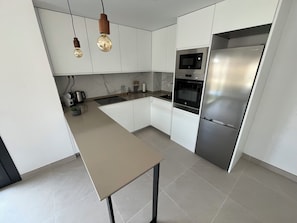 A modern kitchen with white cabinets, a stainless steel refrigerator, a built-in oven, and a light-colored countertop. - Casa Sol y Sombra is located at the stylish Eden Beach residence in Torrevieja. (Torrevieja)