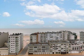 Un quartier résidentiel situé sur la côte, avec des immeubles à plusieurs étages, une plage en arrière-plan et un ciel dégagé.