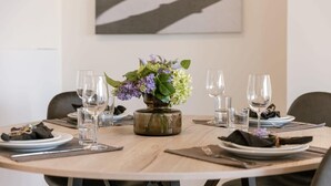 A round dining table with a vase of flowers, plates, cutlery, and glasses. - Trendy apartment close to the coast (Oostende)