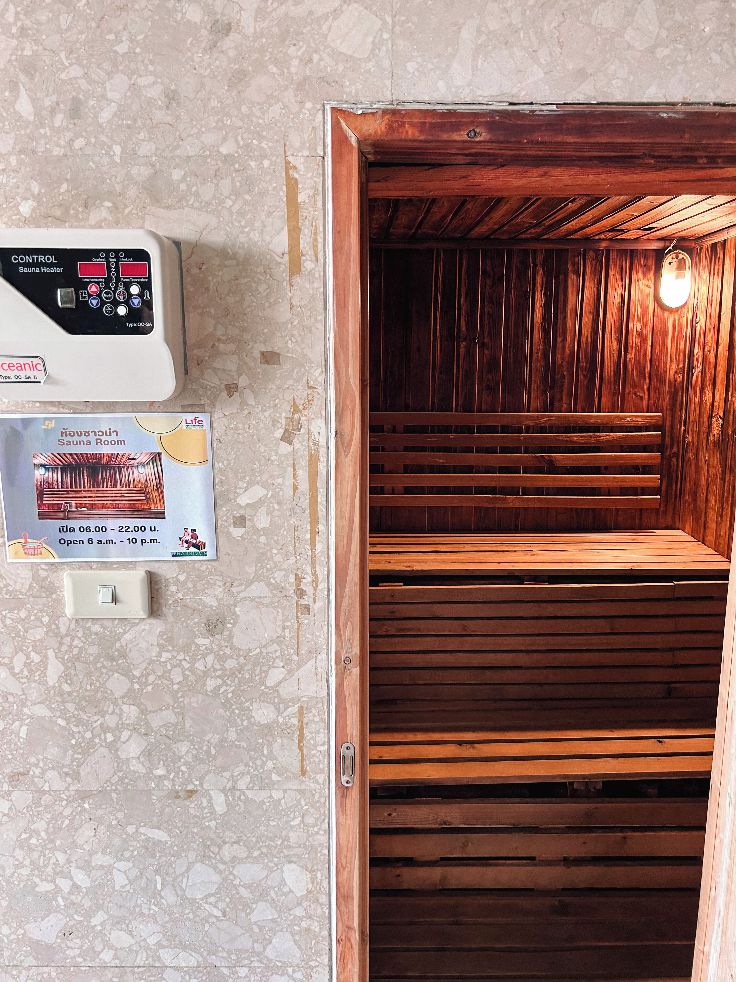 A sauna room with wooden benches and a control panel for the sauna heater.