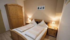 Ein Schlafzimmer mit einem Holzbett, zwei Nachttischen mit Lampen, einem Holzschrank und einem gerahmten Bild an der Wand.