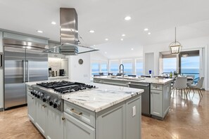 A modern kitchen with a large island, stainless steel appliances, and a view of the ocean. - 30+ Stay, Walk To Beach, W/Amazing Ocean Views (Laguna Beach)
