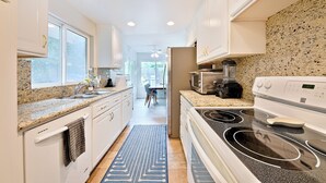 A kitchen with granite countertops, white cabinets, a stove, and a microwave. - Amazing Reviews W/Jacuzzi, Walk 2 Beach, Lrg Yard! (San Diego)