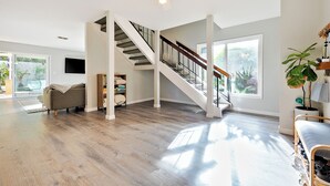 A spacious living area with a staircase, a sofa, and a large window. - Amazing Reviews W/Jacuzzi, Walk 2 Beach, Lrg Yard! (San Diego)