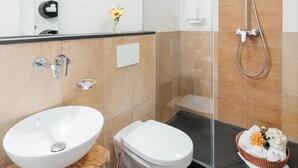 A modern bathroom with a glass shower enclosure, a white sink, and a toilet. - Listed 2-room apartment with historic Lindau ceiling (Lindau)