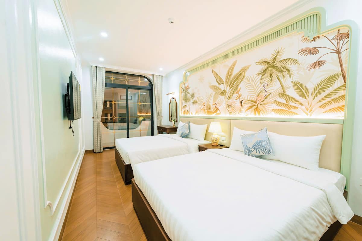Habitación de hotel con dos camas, televisión, puerta corrediza y un mural temático tropical.