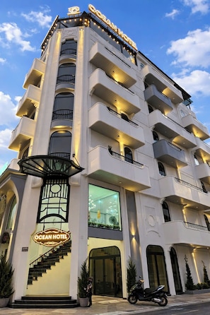 A multi-story hotel with balconies, a large illuminated sign, and a staircase leading to the entrance. - OCEAN HOTEL NINH BINH (Ninh Bình)