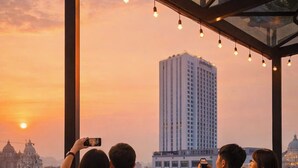 A group of people sitting at a bar with a city view at sunset. - OCEAN HOTEL NINH BINH (Hoa Lu)