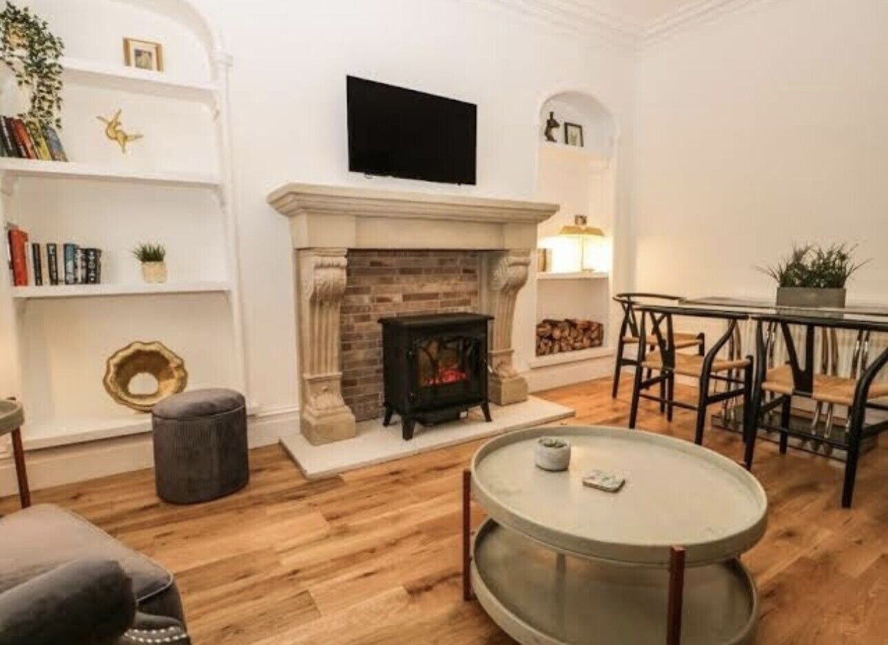 A living room with a fireplace, a round table, and a bookshelf.