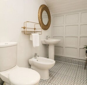 A bathroom with a toilet, bidet, and sink, a gold-framed mirror, and patterned floor tiles. - Stylish Retreat | Sleeps up to 5 | Central Grange | Near Cartmel & Lakes (Grange-over-Sands)