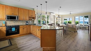 A spacious kitchen with wooden cabinets, a large island, and a view of the ocean.