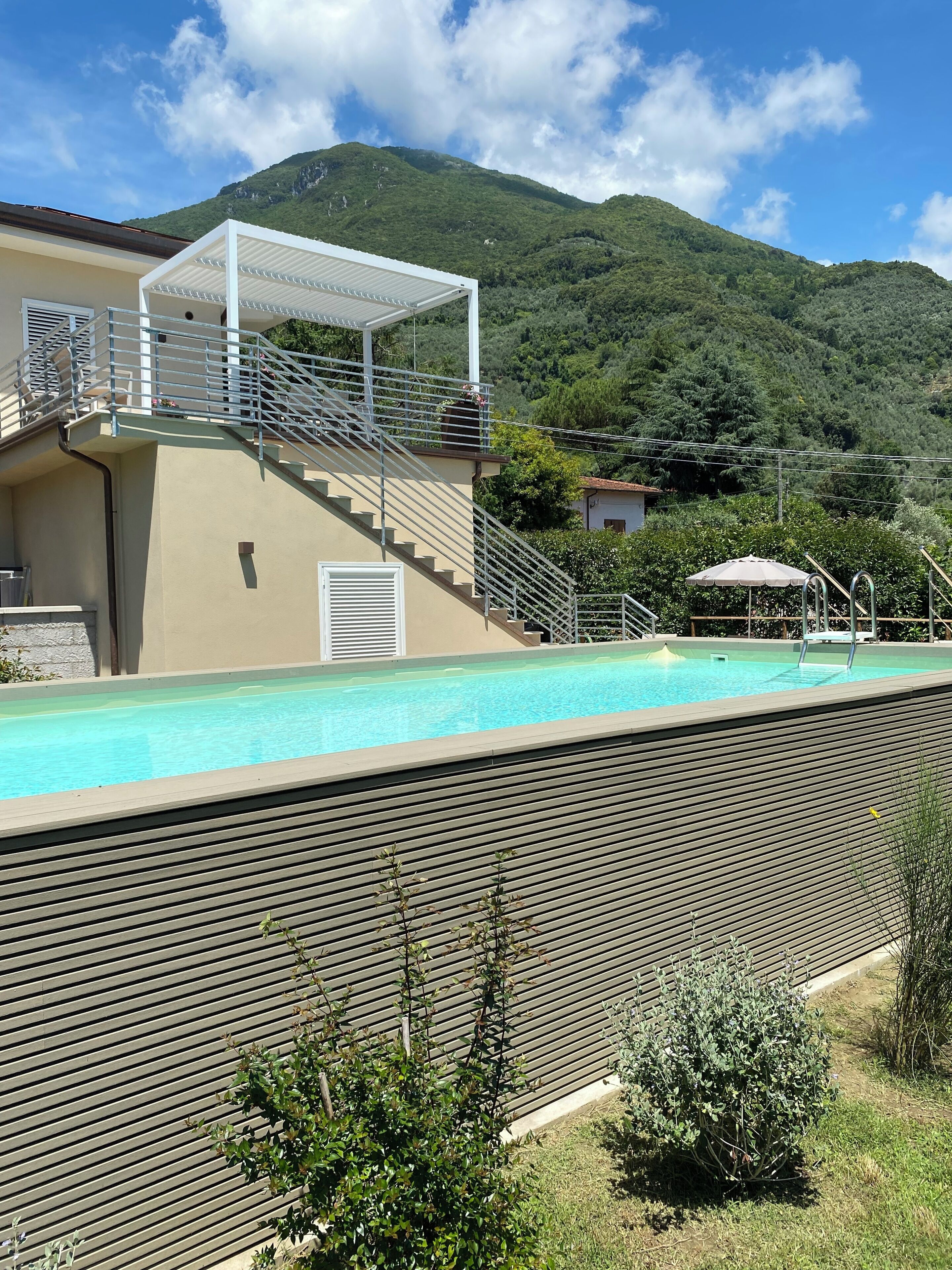 Une piscine dotée d’un espace couvert, d’un escalier et offrant une vue sur une montagne.
