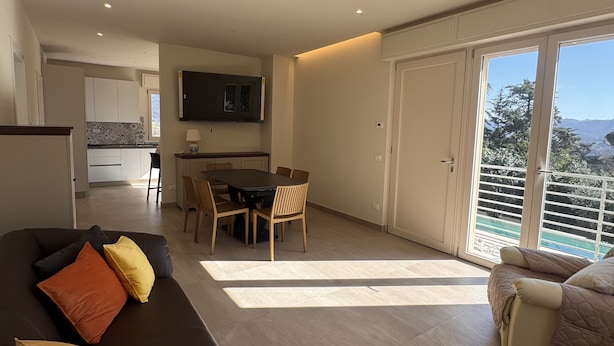 Un salon moderne comprenant un canapé, une table à manger avec des chaises, un coin cuisine et un balcon avec vue.