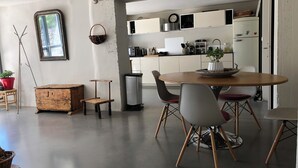 Et moderne køkken med hvide skabe, et spisebord med fire stole og en skraldespand.