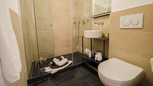 Une salle de bain moderne avec une douche à parois de verre, un lavabo blanc et des toilettes.